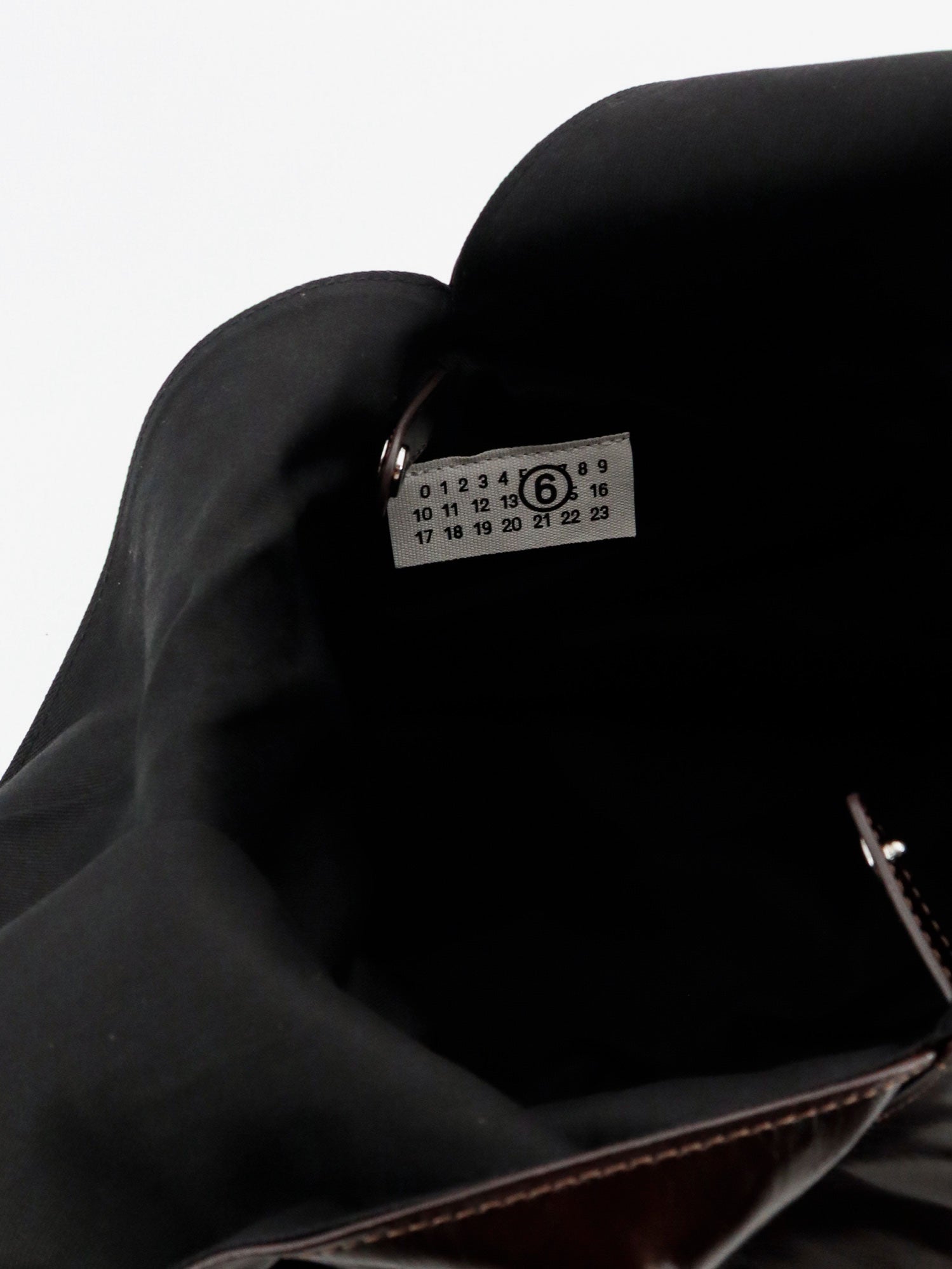 MM6 Maison Margiela shoulder bag showing sculptural metal handle with engraved logo