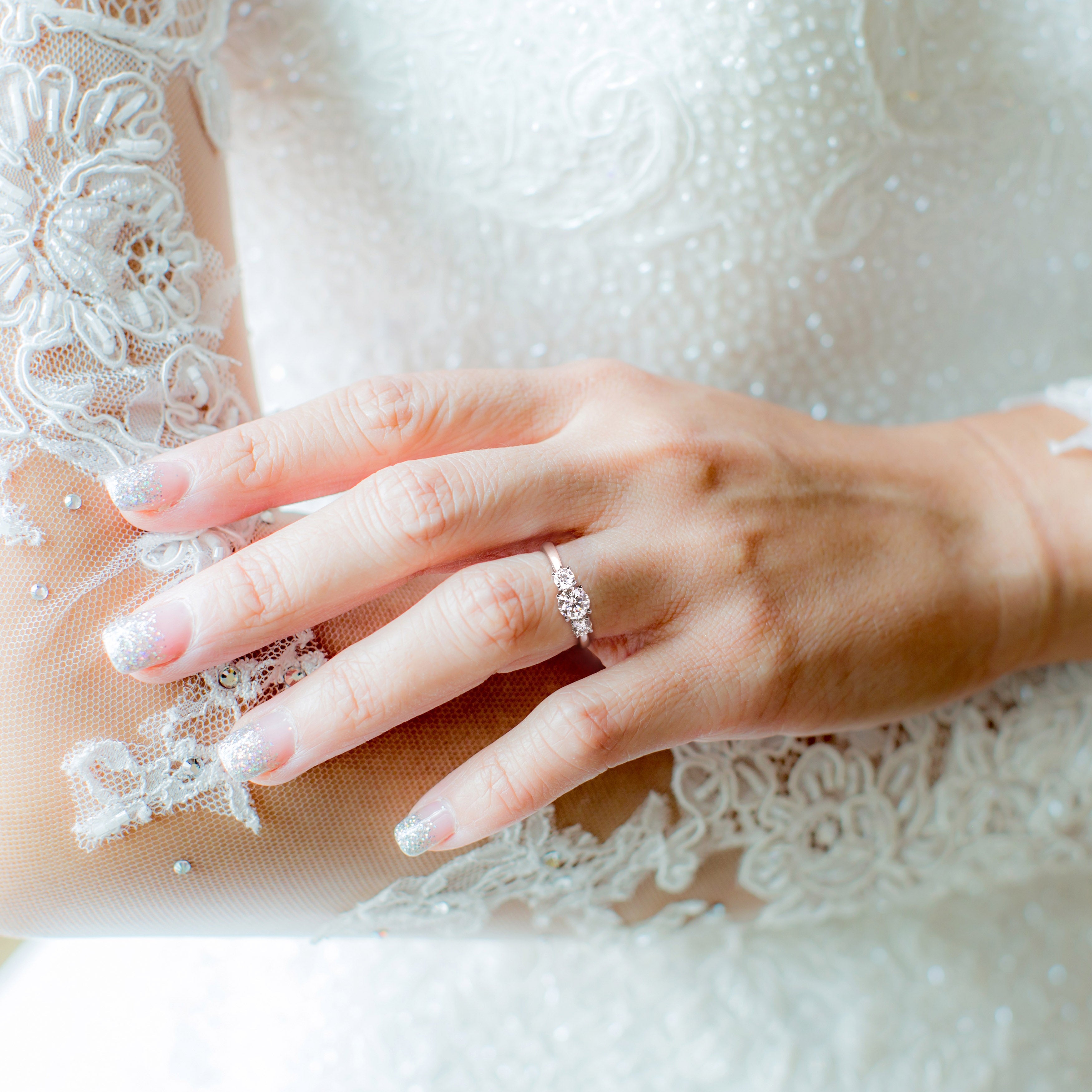 Sterling silver three-stone moissanite ring worn on hand by Lord & Taylor