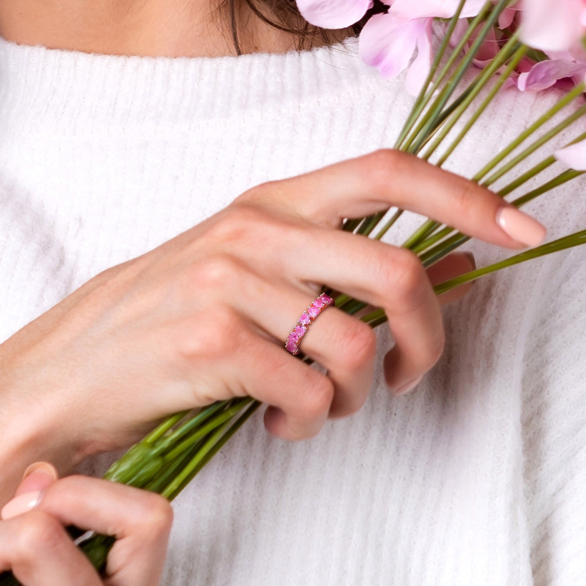 Pink sapphire heart eternity ring in rose-plated sterling silver worn on hand by Lord & Taylor