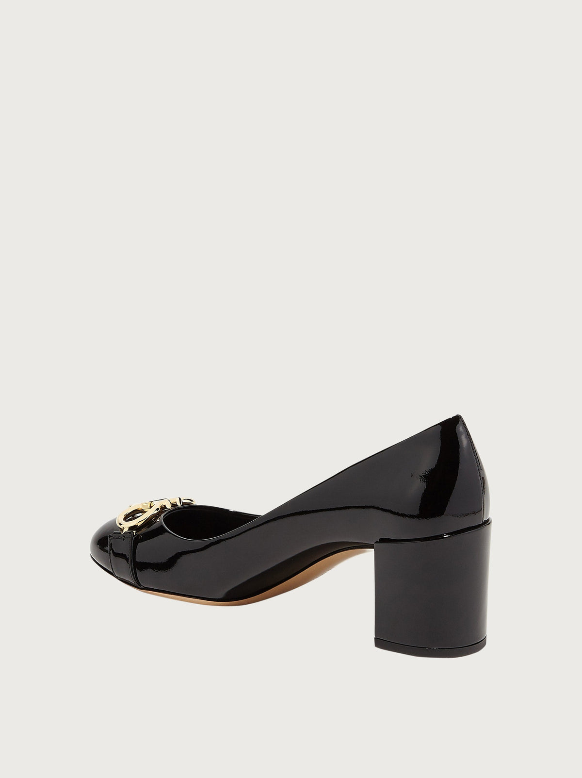Close-up of gold-tone Gancini ornament on black patent leather Ferragamo Garda pump