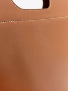 Brown leather tote bag by Loro Piana, overhead view showing open-top design