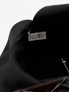 MM6 Maison Margiela shoulder bag showing sculptural metal handle with engraved logo