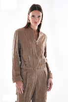 Beige metallic trousers with bomber jacket, side angle showing crinkled fabric texture