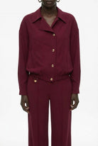 Burgundy bomber jacket detail view showing smooth fluid fabric and seam construction