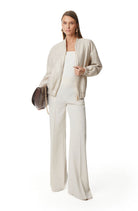 Metallic gold bomber jacket styled with white wide-leg trousers