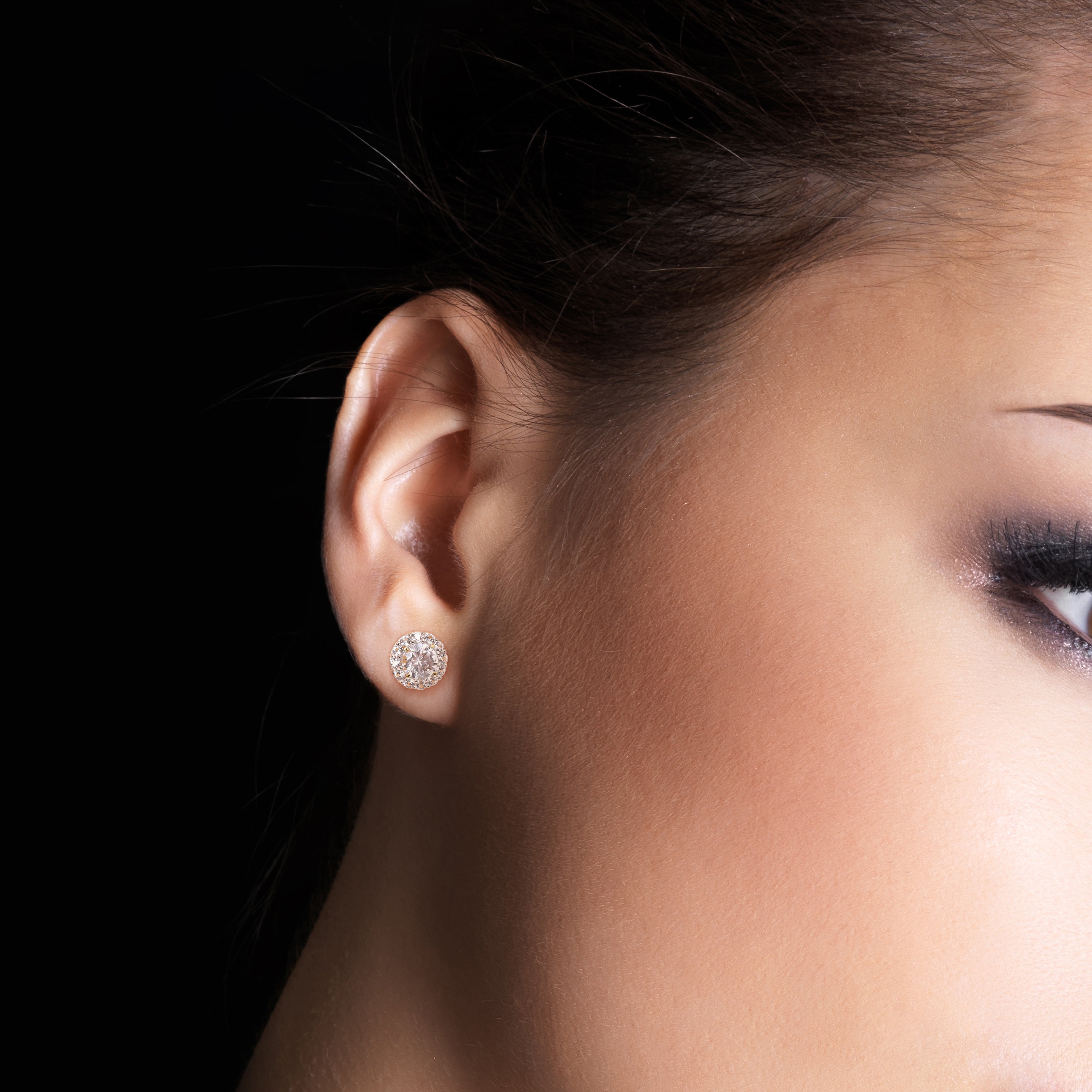 Yellow-plated silver halo stud earrings with white sapphires worn on ear by Lord & Taylor