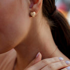 Yellow-plated sterling silver lattice heart stud earrings worn on ear by Lord & Taylor