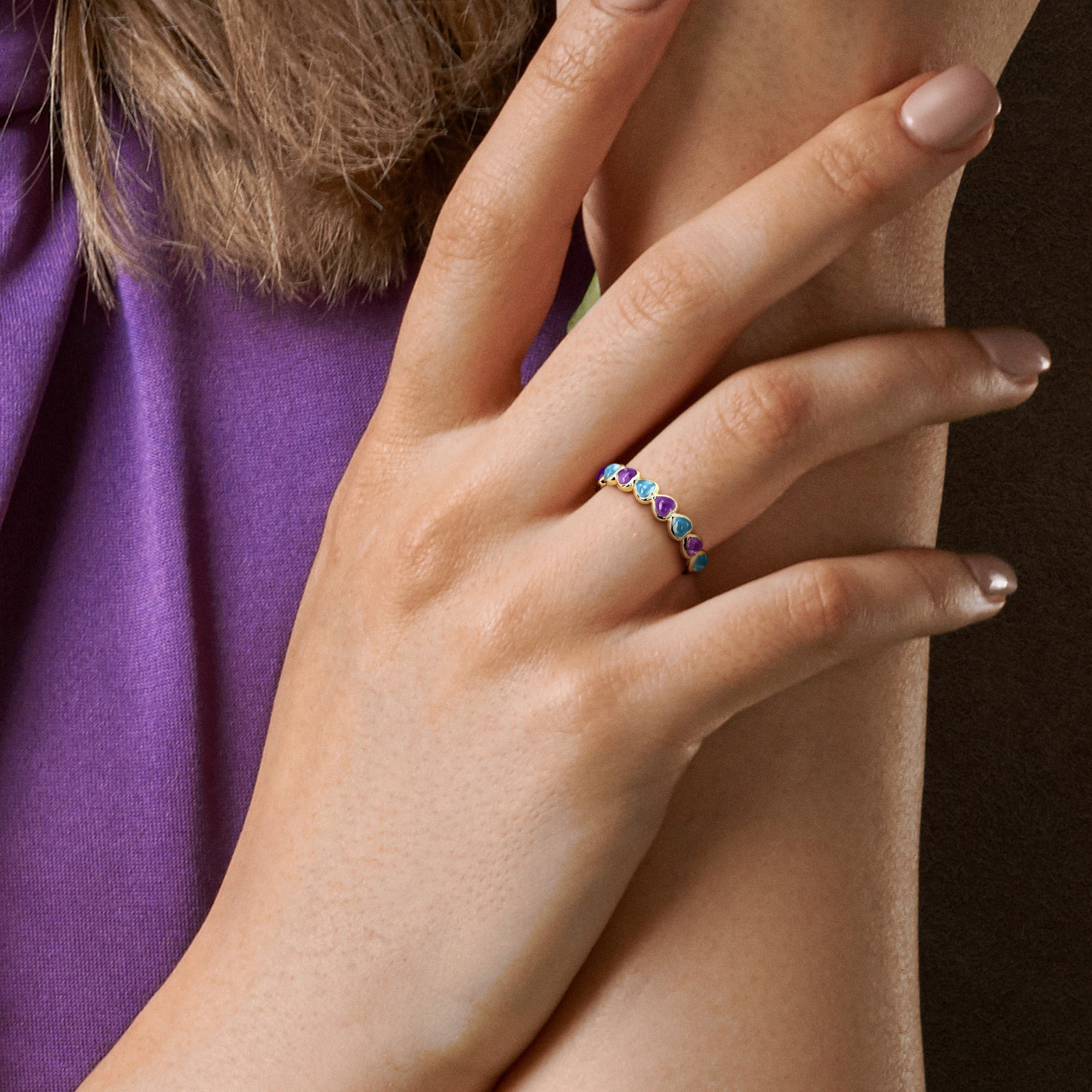 Heart eternity ring with purple and blue gemstones worn on hand by Lord & Taylor