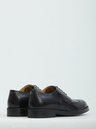 Black patent leather wingtip dress shoes by Tod's, top view showing perforations