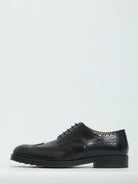 Black patent leather wingtip dress shoes by Tod's, sole view with rubber injection