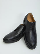Black patent leather wingtip dress shoes by Tod's, detail of embossed monogram