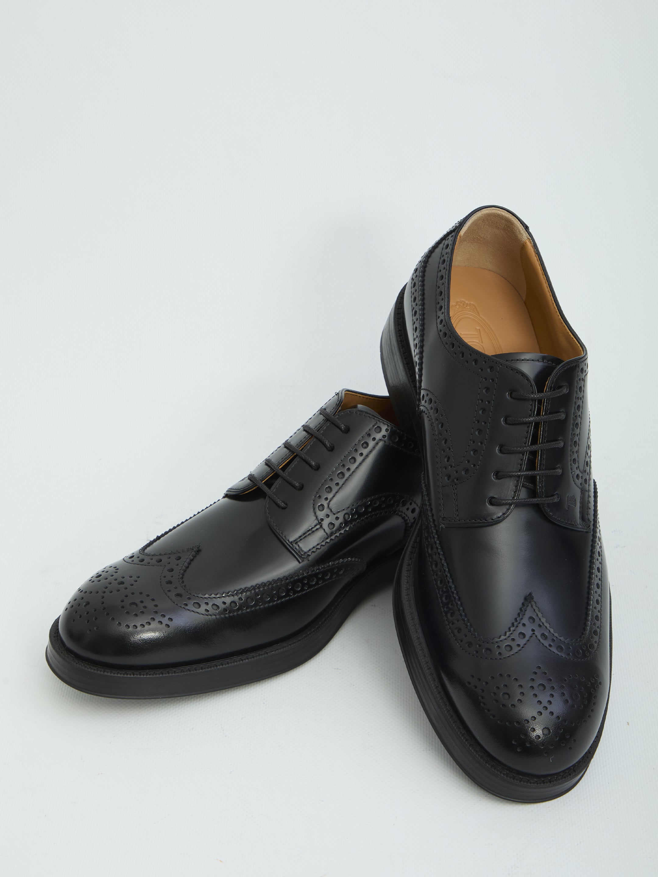 Black patent leather wingtip dress shoes by Tod's, detail of embossed monogram