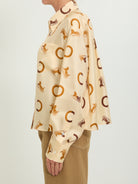 Cream silk twill shirt with brown print by Celine, side view showing cropped length