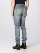 Clay indigo Amiri Thrasher Plus jeans showing ripped knee detail, side angle by Amiri