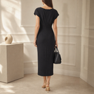 Black midi dress back view showing cascading sash and asymmetric draped hem