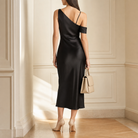 Black satin one-shoulder midi dress back view showing spaghetti strap detail