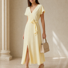 Pale yellow wrap dress V-neckline and self-tie sash detail, close-up front