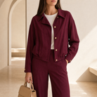 Burgundy bomber jacket front detail showing gold-tone button closure and pointed collar