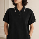 Black cotton polo dress showing shirt collar and striped trim detail, front close-up