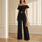Black jumpsuit ruffle neckline and gold-tone belt buckle detail, front close-up